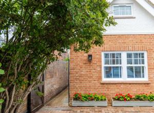 a brick house with two windows and flowers in front of it at The Annexe in Cobham