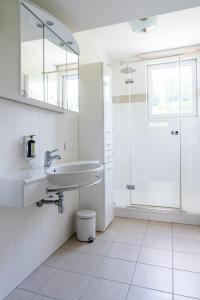 a white bathroom with a sink and a shower at ALPEN ARNIKA Hotel & Restaurant in Tauplitzalm +199 photos