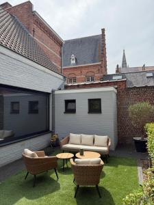 a patio with a couch and chairs and a table at koetshuis in Ieper