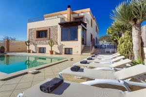 a villa with a row of lounge chairs next to a swimming pool at Villa Campo Sol in Ibiza Town