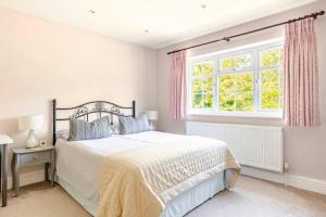 a white bedroom with a bed and a window at Leafy Suburban Bed and Breakfast in Northwood