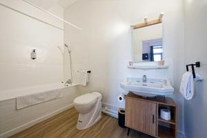 a white bathroom with a sink and a toilet at Hôtel en Ville in Autun
