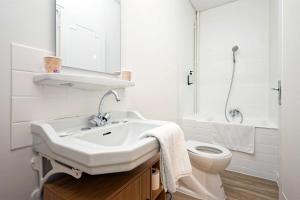 a white bathroom with a sink and a toilet at Hôtel en Ville in Autun +2 photos
