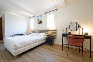 a bedroom with a white bed and a desk at Hôtel en Ville in Autun