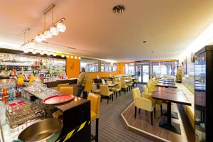 a restaurant with yellow chairs and tables and a bar at Hôtel en Ville in Autun