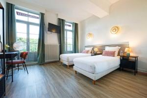 a bedroom with two beds and a table and a desk at Hôtel en Ville in Autun