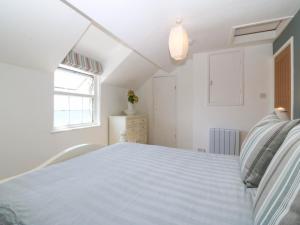 a white bedroom with a bed and a window at 4 Bryn Llan in Pwllheli