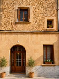 a building with a door and two windows and two potted plants at Sa Torre - Casa Mallorquina con encanto in Campos