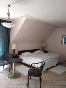 a bedroom with a bed and a table and chairs at Castelinho Apartmanház in Gyenesdiás