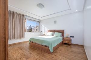 a white bedroom with a bed and a window at Elmoapart in Agadir