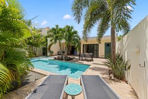 a villa with a swimming pool and palm trees at Luxe Tropische Villa met Privézwembad in Jan Thiel