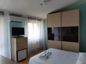 a bedroom with a bed and a dresser with a television at home sweet home in Buia