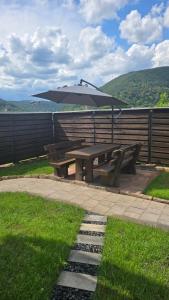 a picnic table with an umbrella next to a fence at Pfälzerblick Lambrecht- Ferienwohnung mit Garten in Lambrecht