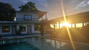 a house with a swimming pool in front of a sunset at Finca campestre Wakanda in Doradal