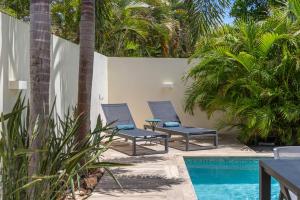two blue chairs sitting next to a swimming pool at Luxe Tropische Villa met Privézwembad in Jan Thiel