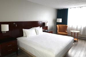 a bedroom with a large white bed and a chair at Travelodge by Wyndham Quebec City Hotel & Convention Centre in Quebec City +58 photos