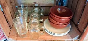 a wooden cabinet with glasses and plates and a pot at Tente équipée in Waimes