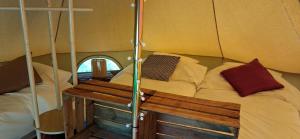 a small room with a bed and two benches in it at Tente équipée in Waimes
