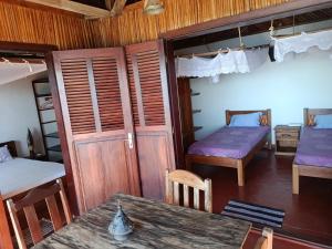 a room with two beds and a table in it at Manta be à Nosy Komba in Ampangorinana
