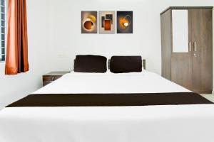 a bedroom with a white bed and a wooden cabinet at Hotel O D'Rooms in Trivandrum