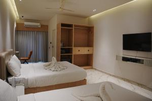 ein Hotelzimmer mit zwei Betten und einem Flachbildfernseher in der Unterkunft Hotel Shellmark in Elivāla