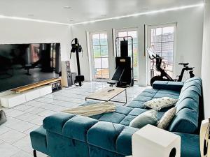 a living room with a blue couch and a gym at Mediterrane Ferienwohnung mit Whirlpool und Weitblick in Merchweiler