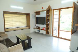a living room with a tv and a couch and a table at NJ Grand Villa in Kālapettai