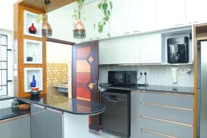 a kitchen with white cabinets and a black counter top at NJ Grand Villa in Kālapettai