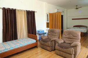 a living room with two chairs and a bed at NJ Grand Villa in Kālapettai