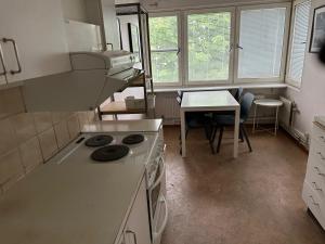 a kitchen with a stove and a table and windows at Apartment in Skarholmen Stockholm 206 in Stockholm