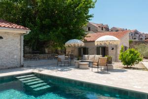 a backyard with a swimming pool with chairs and umbrellas at Doma in Supetar