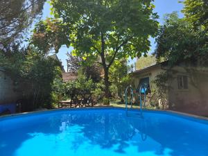 a blue swimming pool with a table and trees at Le Clos du Moulin Dijon, piscine, la campagne à la ville, proche centre historique in Dijon