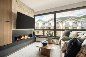 a living room with a fireplace and a large window at Kindred Resort, A RockResort in Keystone
