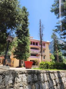 a pink building with a tree in front of it at Grand palace hotel kumrat in Tāl +7 photos