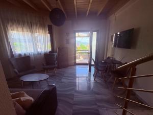 a living room with chairs and tables and a window at Lajes Apartment in Skala Potamias