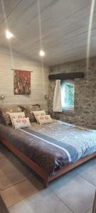 a large bed in a room with a stone wall at La Fleur de Lys in Moulins