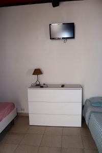 a bedroom with a dresser with a lamp and a tv on the wall at Pantera Rosa Village in Scalea