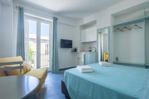 a bedroom with a blue bed and a kitchen at Le Isole di Anita in Lipari