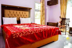 a bedroom with a large bed with a red blanket at Grand palace hotel kumrat in Tāl