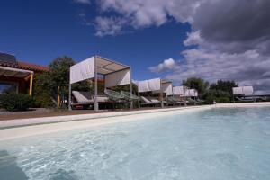 a pool of water with chairs and a building at Casinhas de Santo António in Alter do Chão