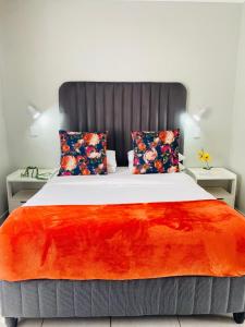 a bedroom with a large bed with a red blanket at Blooming Rose Bed and Breakfast in Polokwane