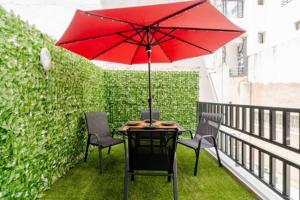 a table and chairs with a red umbrella on a balcony at Studio Chic avec Terrasse Verdoyante in Casablanca
