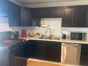 a kitchen with black cabinets and a sink and a stove at Superhero Family Home Near Downtown Amarillo in Amarillo