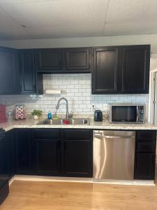 a kitchen with black cabinets and a stainless steel sink at Superhero Family Home Near Downtown Amarillo in Amarillo +3 photos