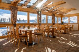 a restaurant with tables and chairs in a room with windows at ALPEN ARNIKA Hotel & Restaurant in Tauplitzalm