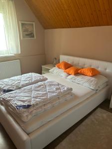 a bed with orange pillows on it in a bedroom at PEP Apartman in Balatonlelle