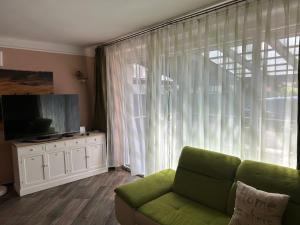 a living room with a green couch and a large window at PEP Apartman in Balatonlelle
