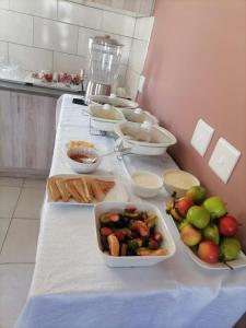 a table with plates of food and bowls of fruit at Blooming Rose Bed and Breakfast in Polokwane