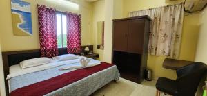 a bedroom with a bed and a chair and a window at Hotel Roy's in Shādipur