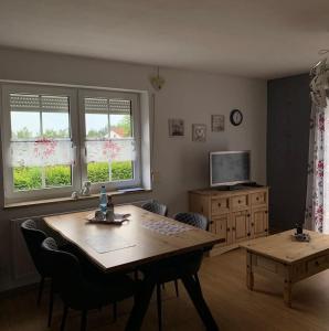 a living room with a wooden table and a television at Bernsteinglück in Wunsiedel +2 photos